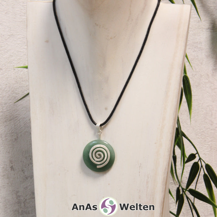 Ein Aventurin Donut an einem Donut-Halter Spirale, der mit einem gewachsten Baumwollband um eine helle Büste hängt.