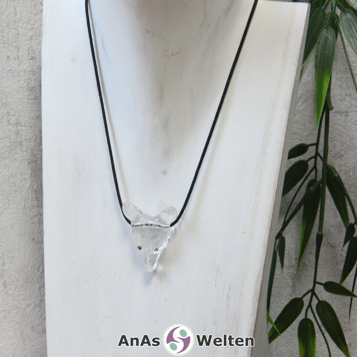 Ein Bergkristall Wolf Anhänger an einem schwarzen Baumwollband, der um eine dunkle Büste gehängt wurde.