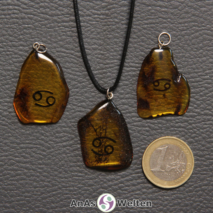 Drei Bernstein Anhänger Krebs in verschiedenen Formen. Das Sternzeichensymbol ist in die Bernsteine eingebrannt.
