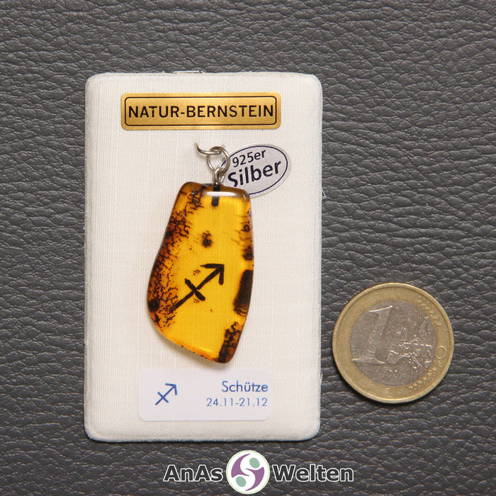 Ein Bernstein Anhänger Schütze mit Silberöse an einem Display. Das Sternzeichen ist in den Bernstein eingebrannt.