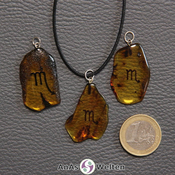 Drei Bernstein Anhänger Skorpion in verschiedenen Formen. Das Sternzeichensymbol ist in die Bernsteine eingebrannt.