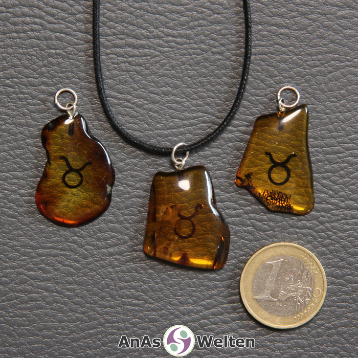 Drei Bernstein Anhänger Stier in verschiedenen Formen. Das Sternzeichensymbol ist in die Bernsteine eingebrannt.