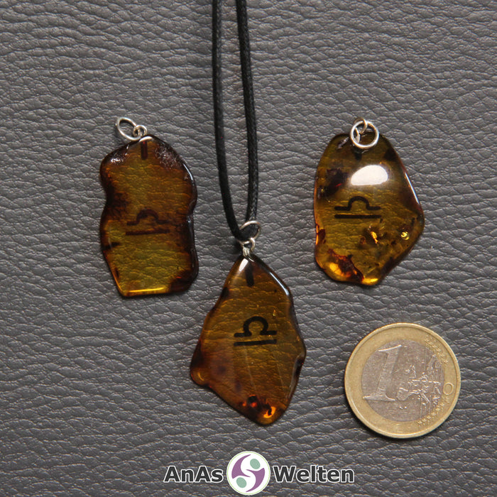 Drei Bernstein Anhänger Waage in verschiedenen Formen. Das Sternzeichensymbol ist in die Bernsteine eingebrannt.