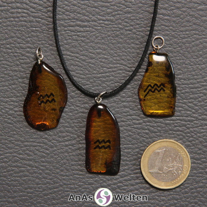 Drei Bernstein Anhänger Wassermann in verschiedenen Formen. Das Sternzeichensymbol ist in die Bernsteine eingebrannt.
