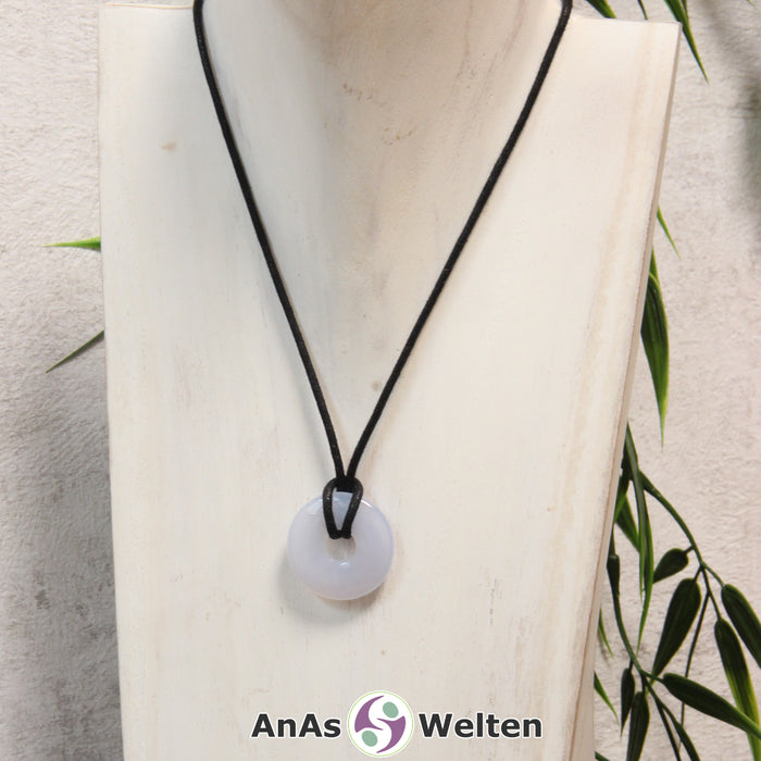 Ein Blauer Chalcedon Donut als Kette an einem schwarzen gewachsten Baumwollband um eine helle Büste.