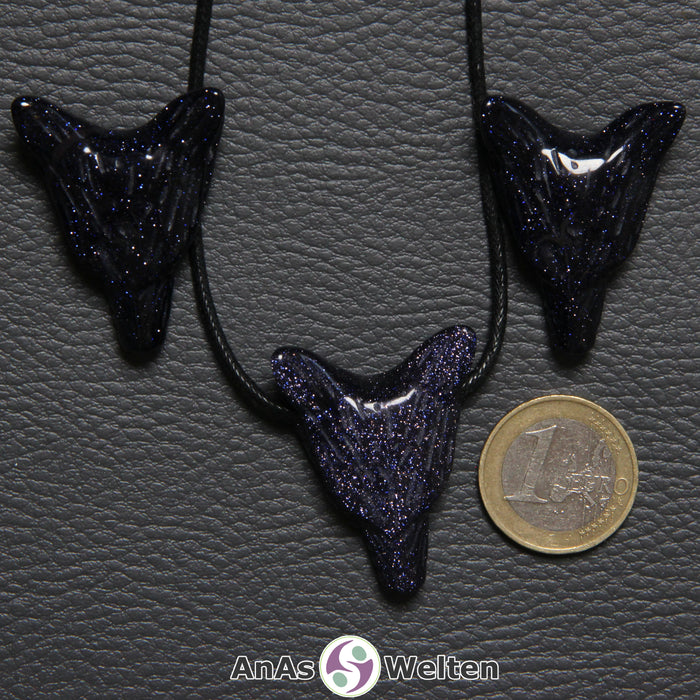 Drei Blaufluss Wolf Anhänger nebeneinander. Einer befindet sich an einem schwarzen Baumwollband.