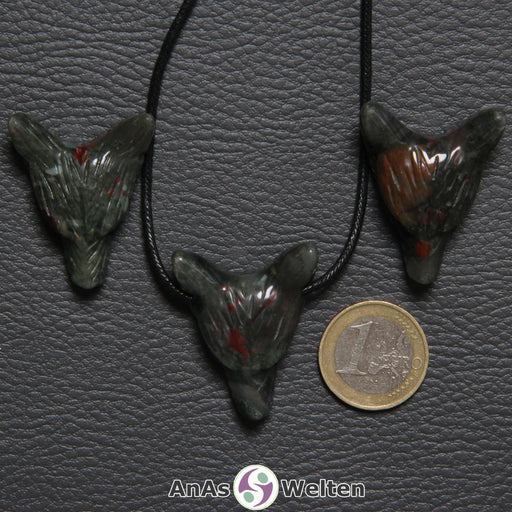 Drei Heliotrop Wolf Anhänger nebeneinander. Einer befindet sich an einem schwarzen Baumwollband.