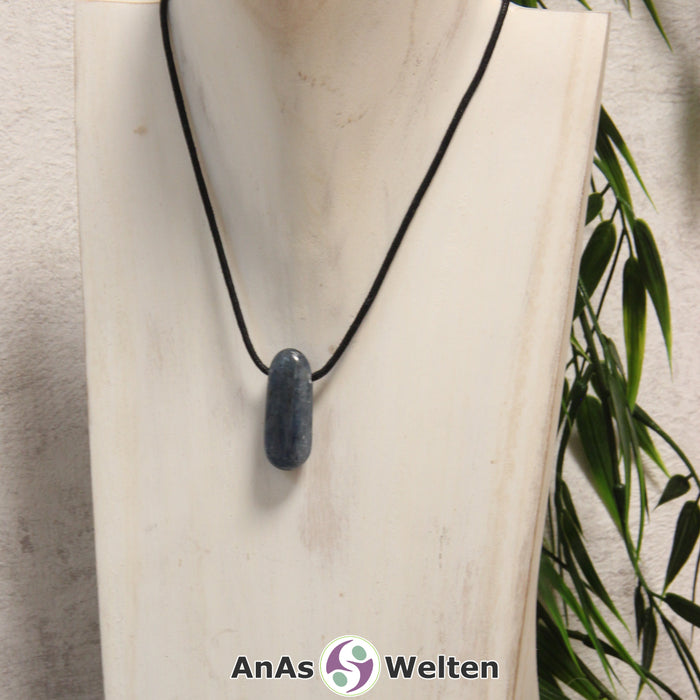 Ein blauer Disthen gebohrter Trommelstein an einem schwarzen Baumwollband, der um eine helle Büste gehängt wurde.