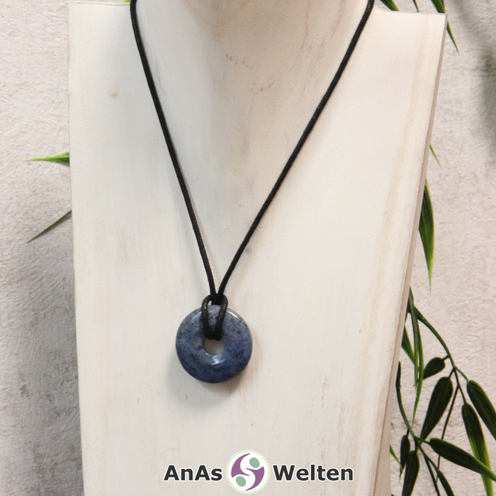 Ein Dumortierit Donut als Kette an einem schwarzen gewachsten Baumwollband um eine helle Büste.