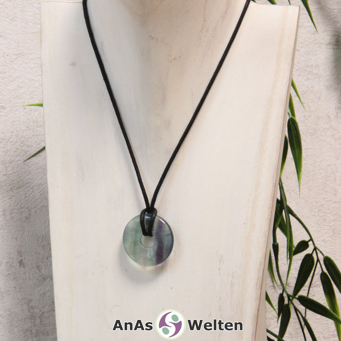 Ein Fluorit Donut als Kette an einem schwarzen gewachsten Baumwollband um eine helle Büste.