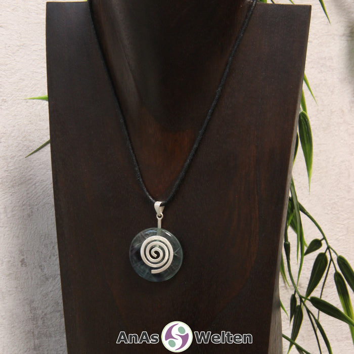 Ein Fluorit Donut an einem Donut-Halter Spirale, der mit einem gewachsten Baumwollband um eine dunkle Büste hängt.