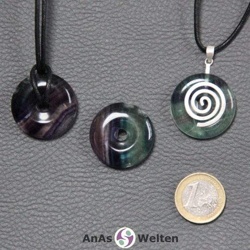 Drei Fluorit Donuts nebeneinander. Einer an einem Baumwollband, ein anderer an einem Donut-Halter mit Baumwollband.