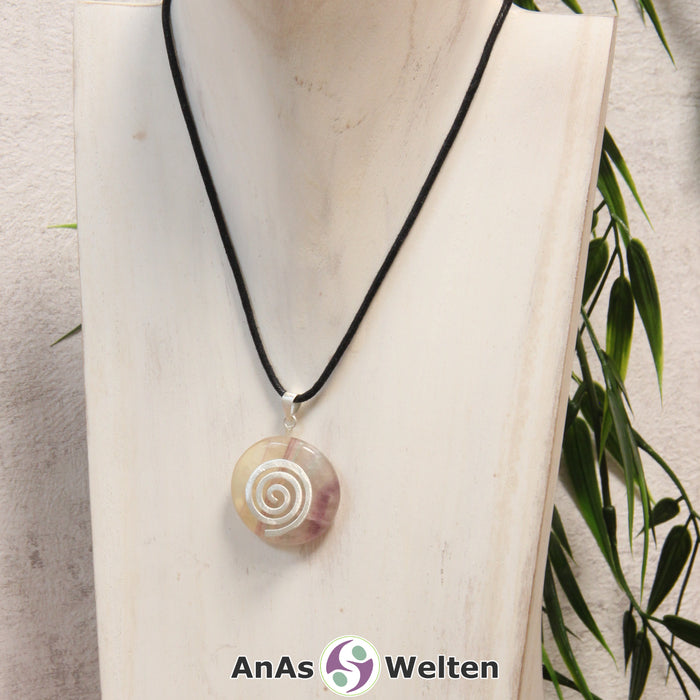 Ein Gelber Fluorit Donut an einem Donut-Halter Spirale, der mit einem gewachsten Baumwollband um eine helle Büste hängt.