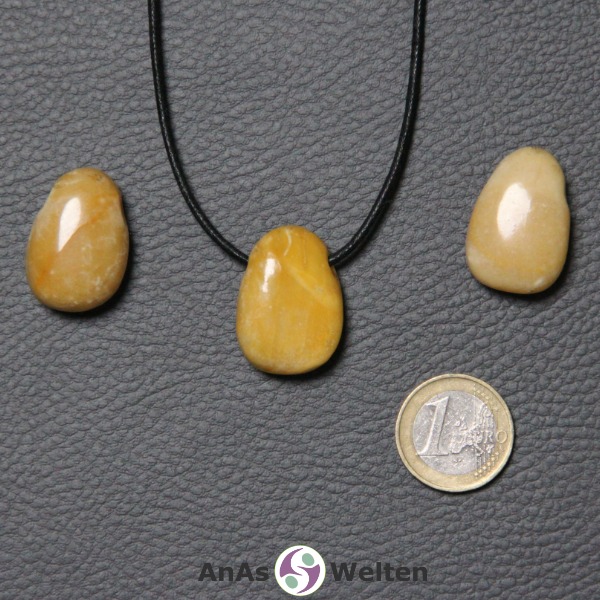 Drei Gelber Jaspis gebohrte Trommelsteine nebeneinander. Einer befindet sich an einem schwarzen gewachsten Baumwollband.
