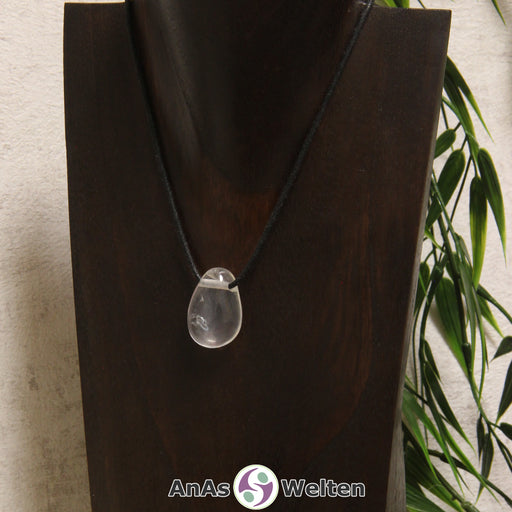 Ein gebohrter Girasol Trommelstein an einem Baumwollband. Der Edelstein hat eine schwach milchige, fast vollkommen durchsichtige Farbe.