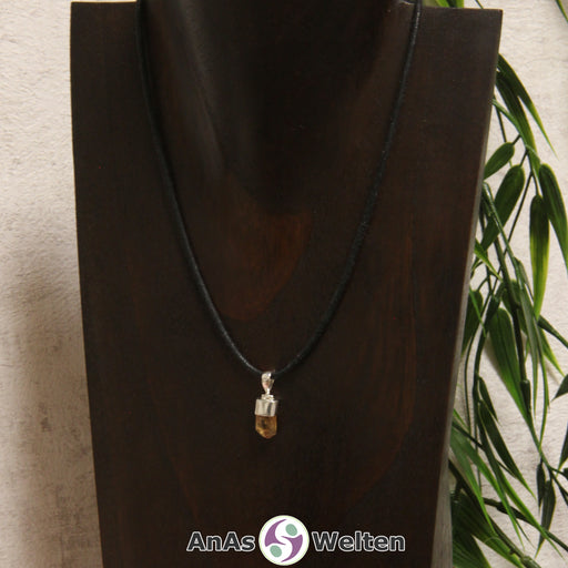 Das Bild zeigt einen Goldtopas mit Öse. Der Edelstein ist gel-orange und durchsichtig. Er ist vergleichsweise klein und hat eine Halterung mit Silberöse.