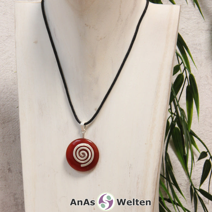 Ein Karneol Donut an einem Donut-Halter Spirale, der mit einem gewachsten Baumwollband um eine helle Büste hängt.