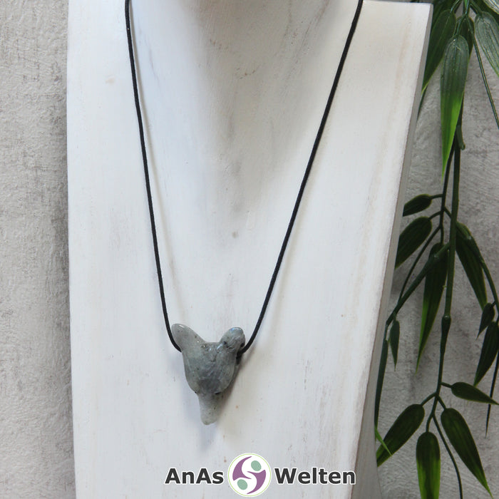 Ein Labradorit Wolf Anhänger an einem schwarzen Baumwollband, der um eine dunkle Büste gehängt wurde.