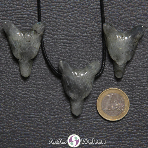 Drei Labradorit Wolf Anhänger nebeneinander. Einer befindet sich an einem schwarzen Baumwollband.