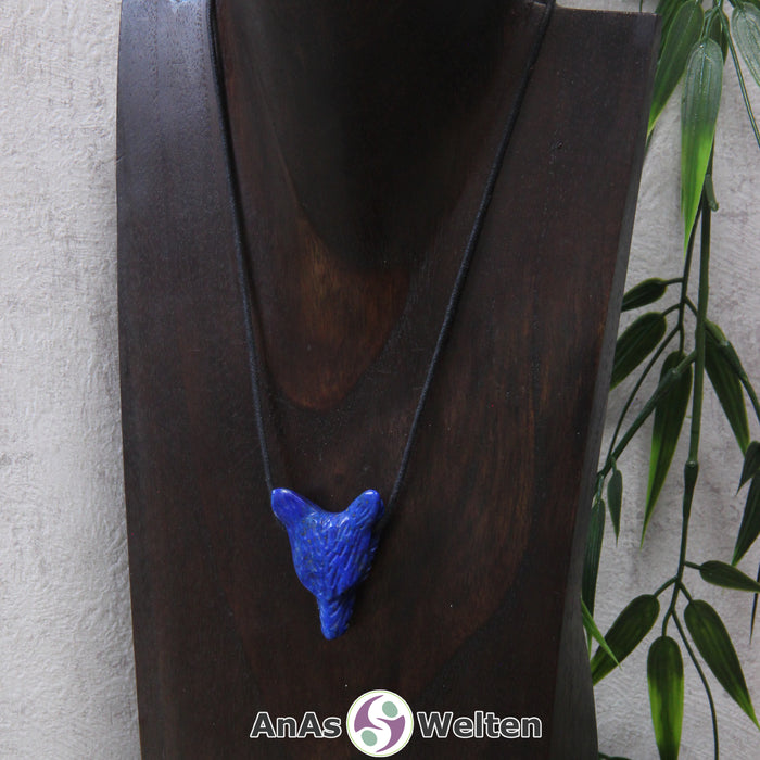 Ein Lapislazuli Wolf Anhänger an einem schwarzen Baumwollband, der um eine dunkle Büste gehängt wurde.
