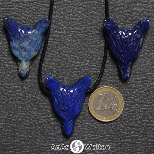Drei Lapislazuli Wolf Anhänger nebeneinander. Einer befindet sich an einem schwarzen Baumwollband.