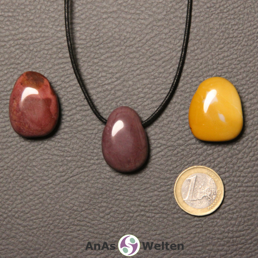 Drei rote und gelbe Mookait gebohrte Trommelsteine nebeneinander. Einer befindet sich an einem schwarzen gewachsten Baumwollband.