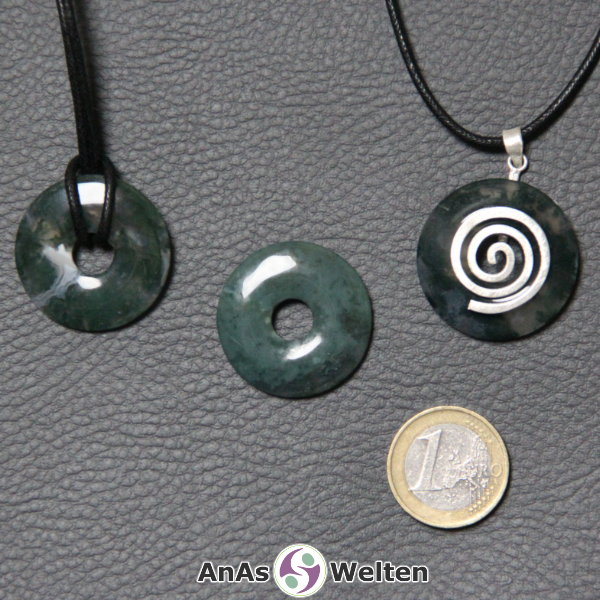 Drei Moosachat Donuts nebeneinander. Einer an einem Baumwollband, ein anderer an einem Donut-Halter mit Baumwollband.