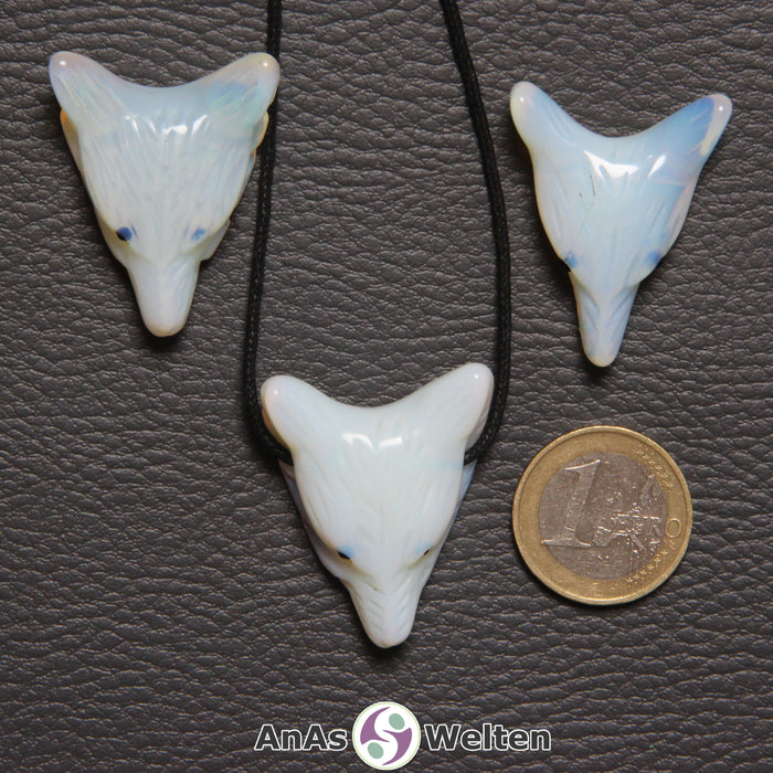 Drei Opalglas Wolf Anhänger nebeneinander. Einer befindet sich an einem schwarzen Baumwollband.