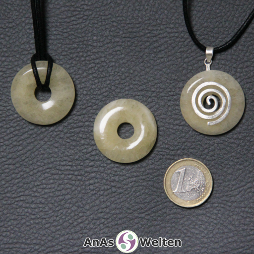 Drei Orangencalcit Donuts nebeneinander. Einer an einem Baumwollband, ein anderer an einem Donut-Halter mit Baumwollband.