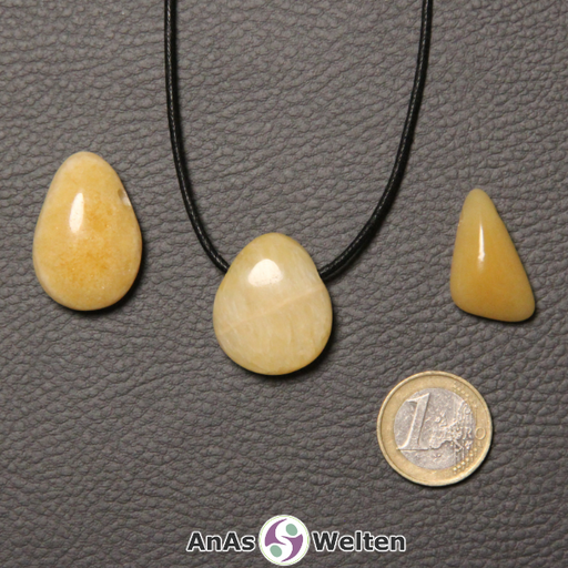 Drei gelbe Orangencalcit gebohrte Trommelsteine nebeneinander. Einer befindet sich an einem schwarzen gewachsten Baumwollband.