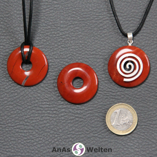 Drei Roter Jaspis Donuts nebeneinander. Einer an einem Baumwollband, ein anderer an einem Donut-Halter mit Baumwollband.