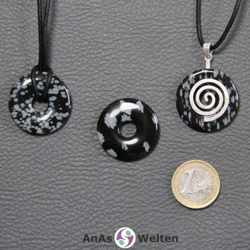 Drei Schneeflocken-Obsidian Donuts nebeneinander. Einer an einem Baumwollband, ein anderer an einem Donut-Halter mit Baumwollband.