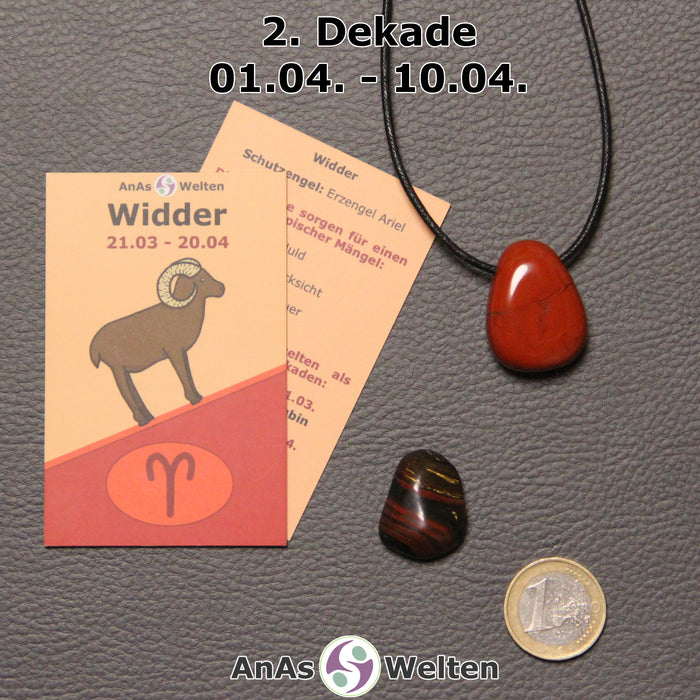 Die Sternzeichenkarte und je ein beispielhafter gebohrter Roter Jaspis am Band und ein Tigereisen Trommelstein der 2. Dekade liegen nebeneinander.