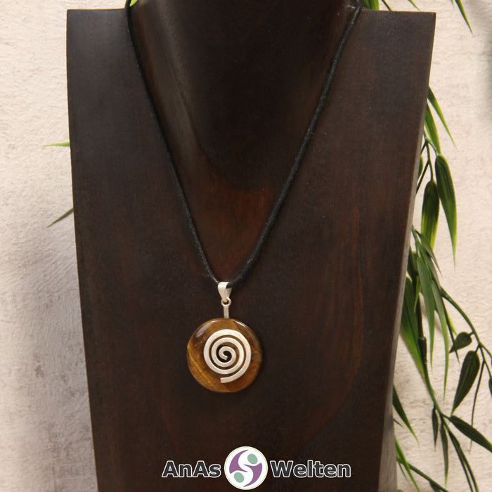 Ein Tigerauge Donut an einem Donut-Halter Spirale, der mit einem gewachsten Baumwollband um eine dunkle Büste hängt.