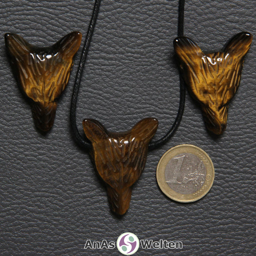 Drei Tigerauge Wolf Anhänger nebeneinander. Einer befindet sich an einem schwarzen Baumwollband.