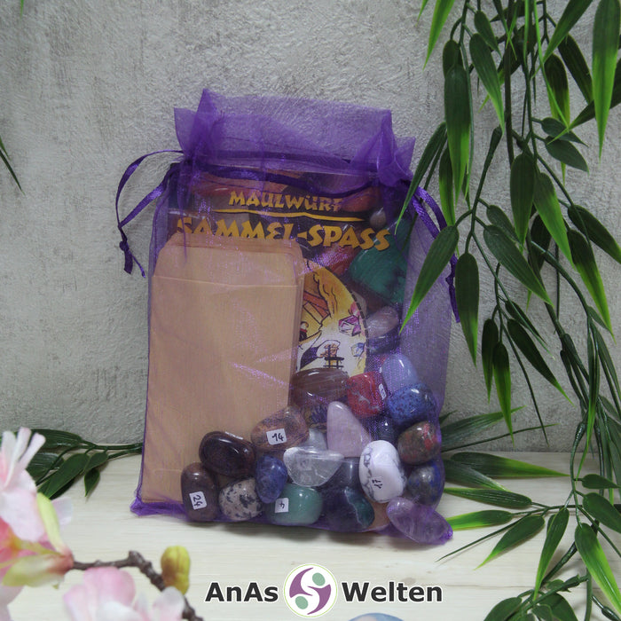 Das Maulwurf Trommelsteine Set mit Edelsteinen, Heft, Stickern und Tüten in einem lila Organzasäckchen.