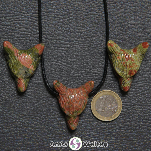 Drei Unakit Wolf Anhänger nebeneinander. Einer befindet sich an einem schwarzen Baumwollband.