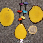 Drei gelbe Tagua-Nuss-Scheiben. Eine davon ist mit 6 Tagua-Nuss-Splittern in den Chakra-Farben als Kette gebunden.