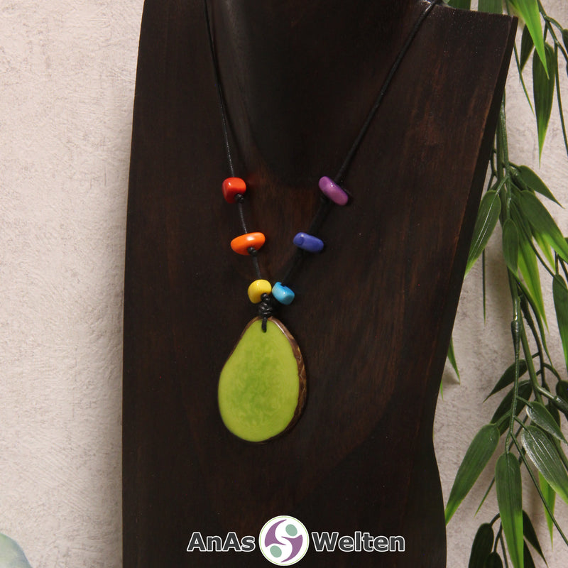 Eine grüne Tagua-Nuss Scheibe als Chakra Kette mit 6 Tagua-Splittern in den anderen Chakrafarben an einer dunklen Büste.