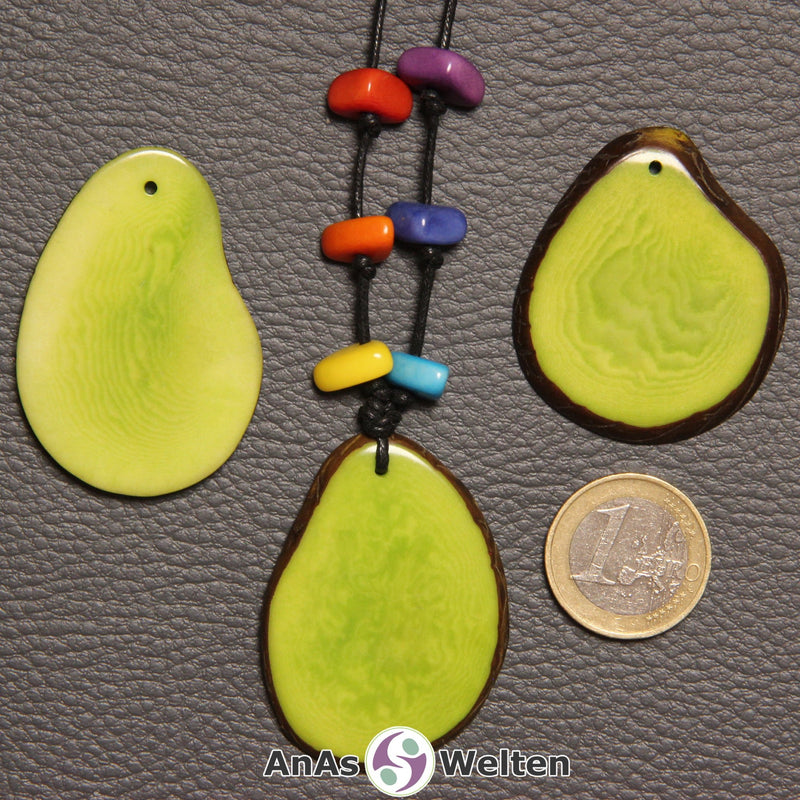 Drei grüne Tagua-Nuss-Scheiben. Eine davon ist mit 6 Tagua-Nuss-Splittern in den Chakra-Farben als Kette gebunden.