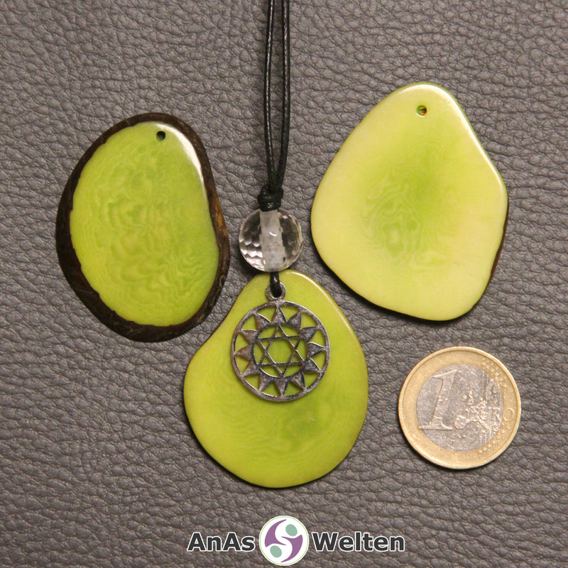 Drei grün gefärbte Tagua-Nuss-Scheiben. Eine davon ist als Kette mit Bergkristall und 4. Chakra Symbol gebunden.