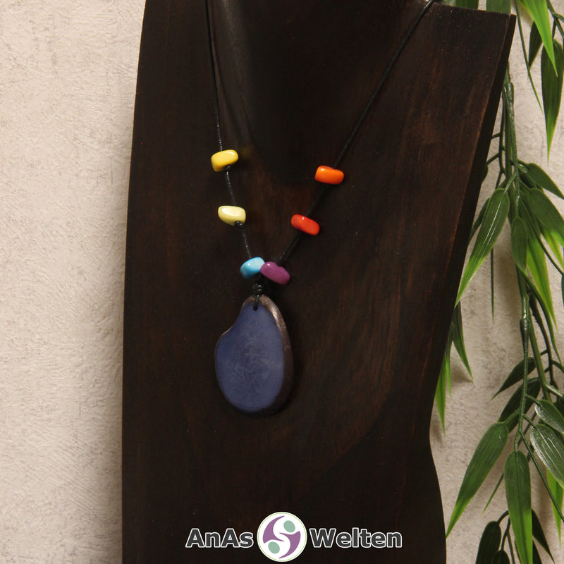 Eine blaue Tagua-Nuss Scheibe als Chakra Kette mit 6 Tagua-Splittern in den anderen Chakrafarben an einer dunklen Büste.