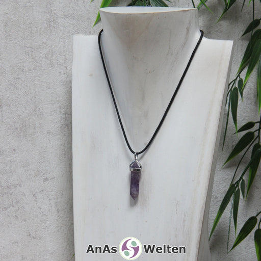 Das Produktbild zeigt einen Amethyst Stift-Anhänger groß an einem Baumwollband. Es handelt sich um einen Stift-Anhänger mit Doppelspitze in einer lila-weißen Farbe. Direkt unterhalb der oberen Spitze ist ein glänzendes Metallelement befestigt, das oberen Ende einen Bogen mit einer Öse hat.