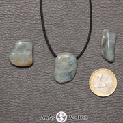 Drei blaue Aquamarin gebohrte Trommelsteine nebeneinander. Einer befindet sich an einem schwarzen gewachsten Baumwollband.