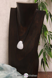 Ein Blauer Calcit gebohrter Trommelstein an einem schwarzen Baumwollband, der um eine dunkle Büste gehängt wurde.