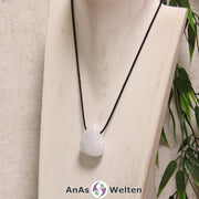 Ein Blauer Calcit gebohrter Trommelstein an einem schwarzen Baumwollband, der um eine helle Büste gehängt wurde.