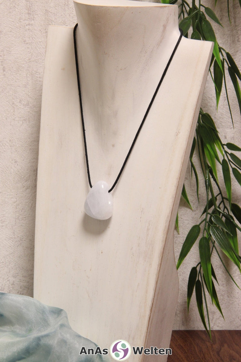 Ein Blauer Calcit gebohrter Trommelstein an einem schwarzen Baumwollband, der um eine helle Büste gehängt wurde.