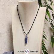 Ein Dumortierit Stift-Anhänger groß mit Metallöse, der mit einem schwarzen Baumwollband um eine helle Büste gehängt wurde