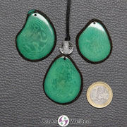 Drei Tagua-Nuss-Scheiben in Grün. Die mittlere ist mit einer Bergkristallkugel an ein schwarzes Baumwollband gebunden.