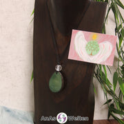 Ein grüner Tagua-Nuss Engel Anhänger ist als Kette mit einer Bergkristallkugel um eine dunkle Büste gehängt.